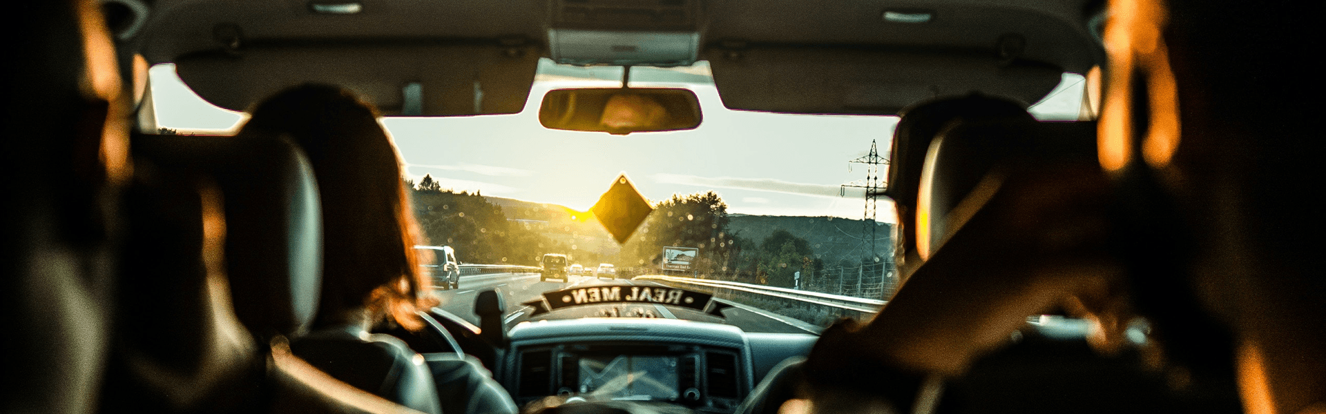 Mitfahrer:innen teilen sich eine Autofahrt auf der Autobahn bei Sonnenuntergang